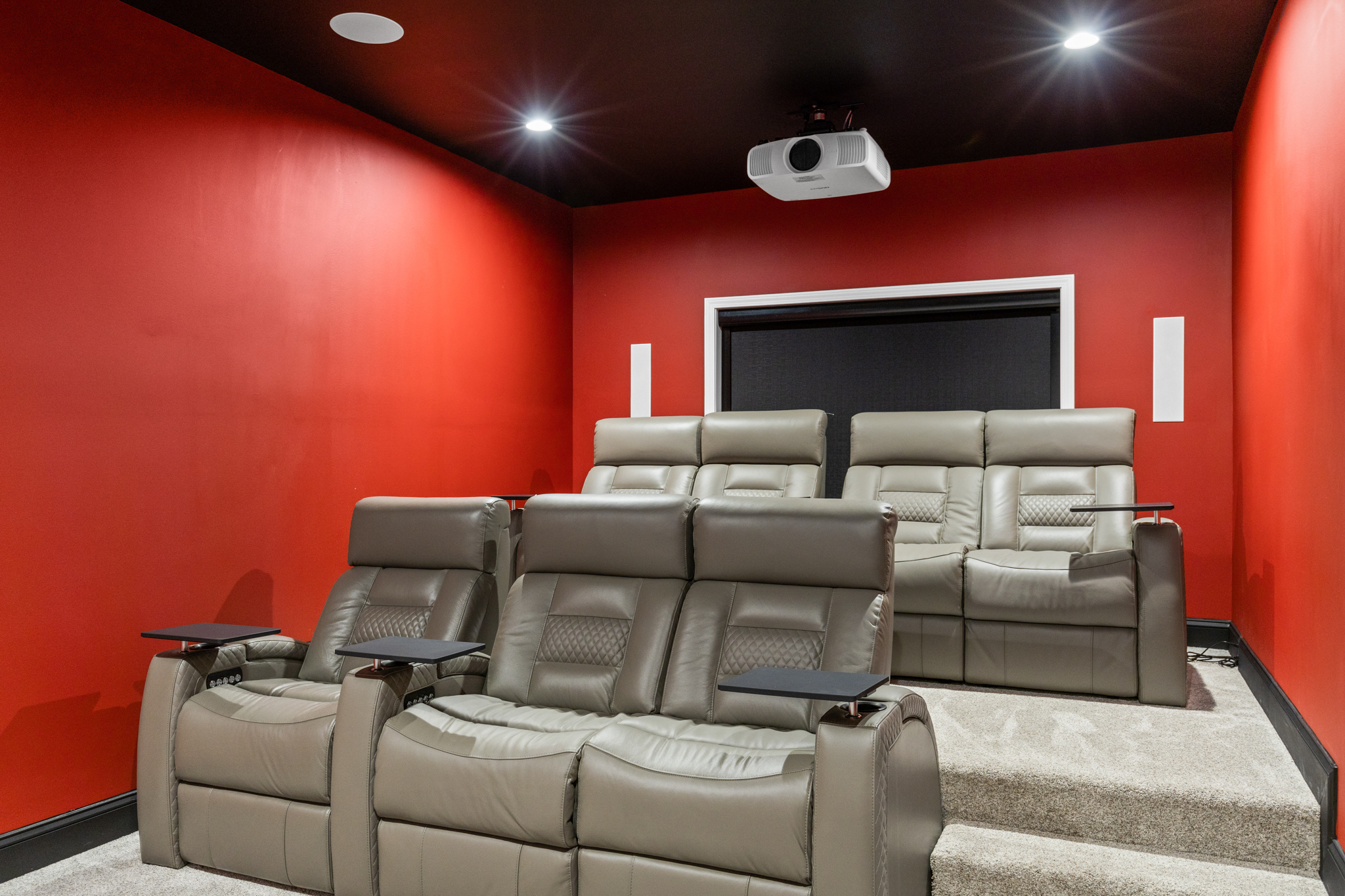 Home theater with red walls and tiered leather recliners