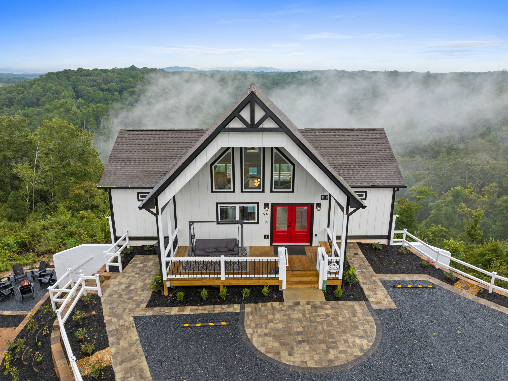 Modern farmhouse cabin front with red door and evening mist