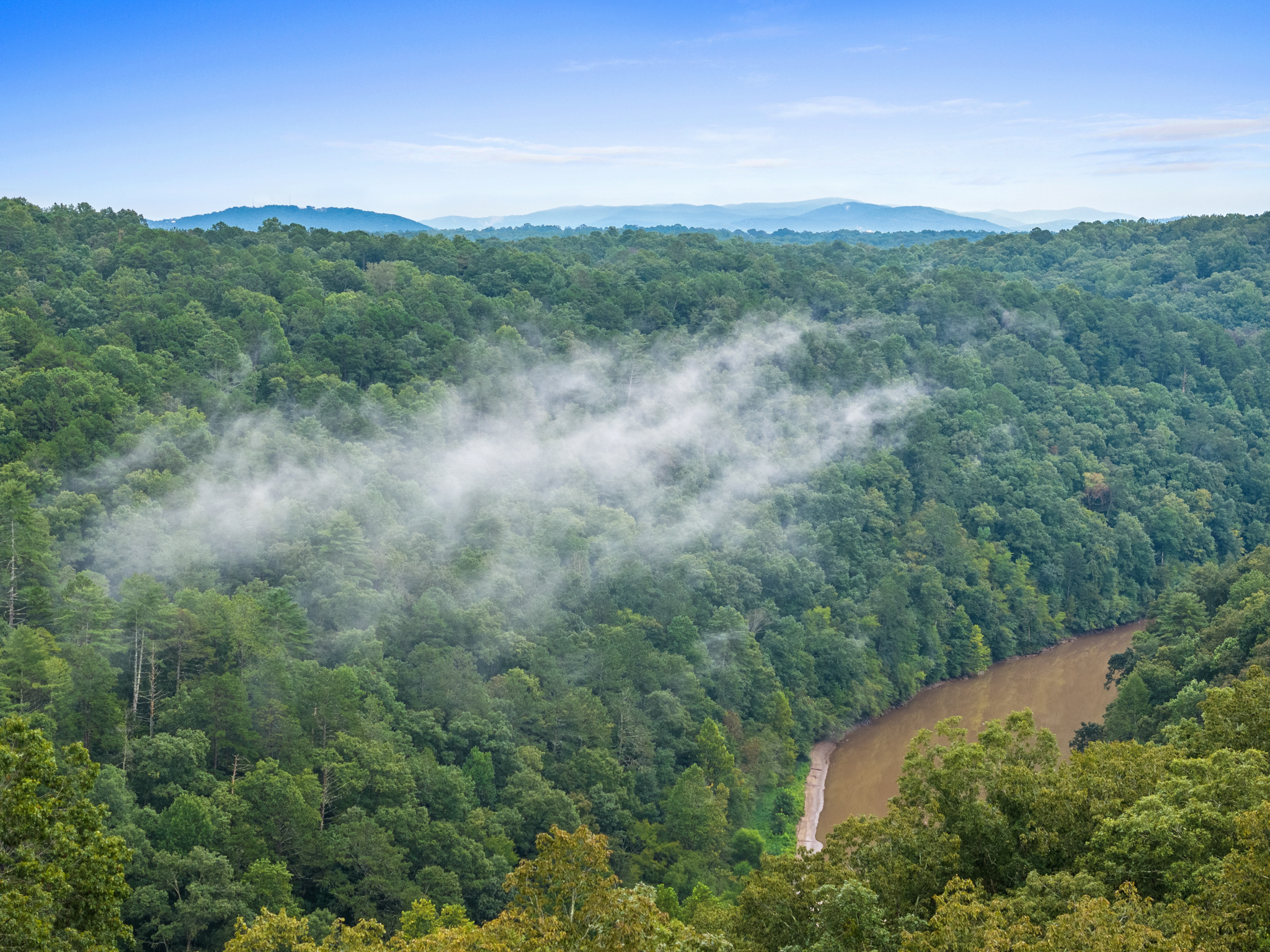 River winding through valley with evening rain mist